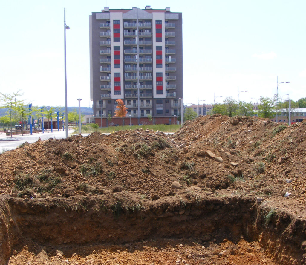 Sondeo arqueológico previo en un sector de nueva urbanización, con edificios residenciales al fondo